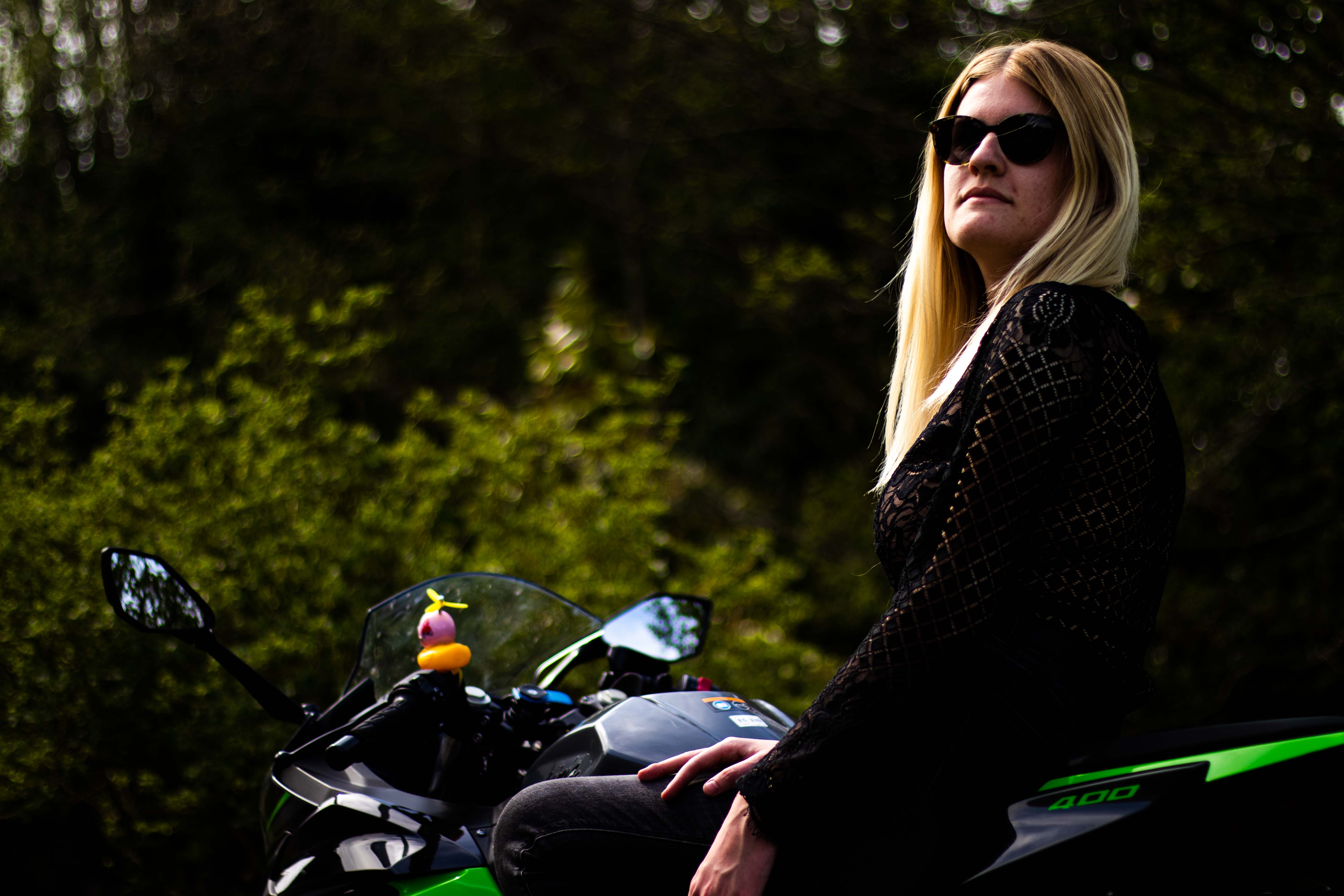 Photo d'une femmme assise sur une moto avec le regard horp champ au trois quart dos